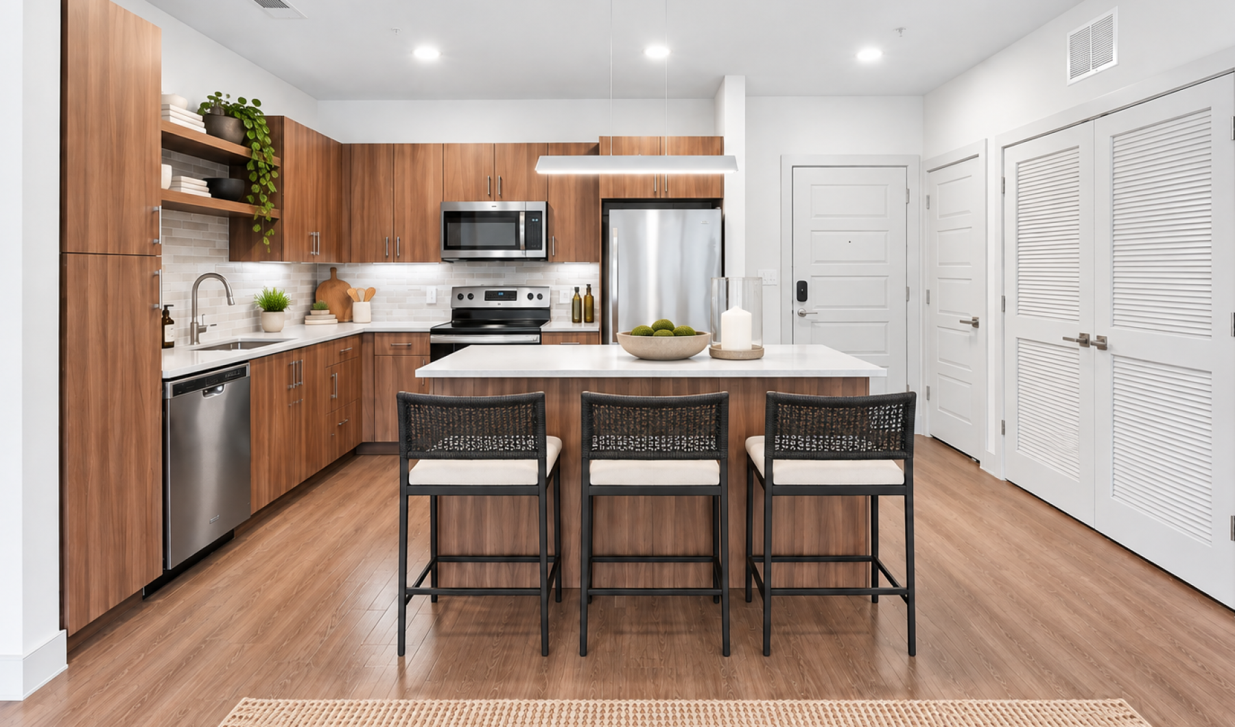 Modern apartment kitchen at The Ian in Herndon, VA, with an island breakfast bar, stainless steel appliances, and wood-style floors